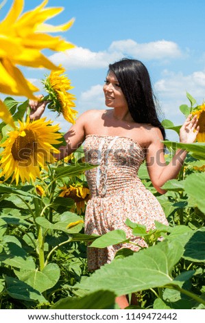Beautiful joyful girl in a field of sunflowers enjoying nature against the blue sky.