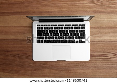 Modern laptop on wooden table, top view