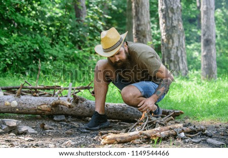 Ultimate guide to bonfires. How to build bonfire outdoors. Arrange the woods twigs or wood sticks standing like a pyramid and place the leaves under. Man straw hat prepares bonfire in forest.