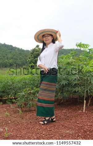 Thailand women wearing a green sarong and white shirt standing in a cassava plantation on the hill.