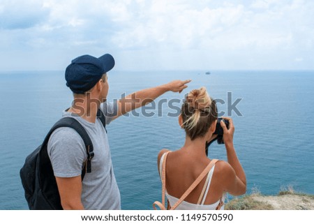 Young couple traveling. Girl taking pictures of the landscape