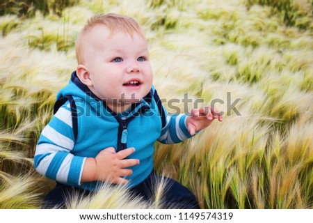 Child is sitting in the grass and looks away