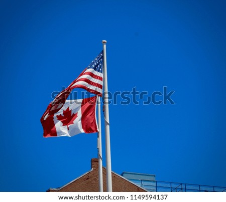 Canadian and American Flag flying in Portland Maine with a Bright Blue Sky on a Sunny Summer’s Day