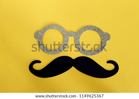 Black man's mustache, gold glasses with glitter, yellow background. Accesoris of man, symbol for parties, play having fun