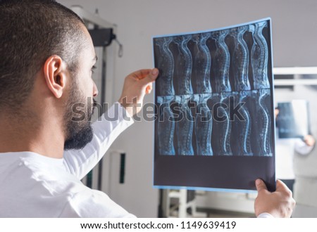 Radiologist analysing X-ray image with human spine in consulting room Royalty-Free Stock Photo #1149639419