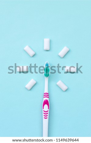 Toothbrush and chewing gums lie on a pastel blue background. Top view, flat lay. Minimal concept