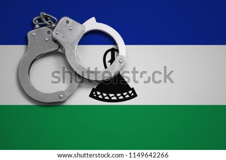 Lesotho flag  and police handcuffs. The concept of crime and offenses in the country