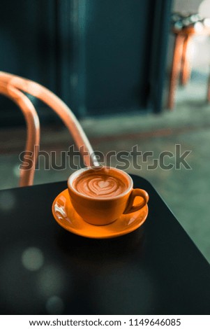 Flat white coffee in yellow cup on a wooden table at the hipster coffee shop. Latte art concept. Dark food photo. Vintage color tones, filter effect. Copyspace; vertical