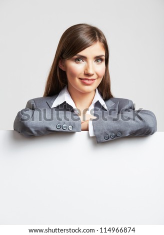Smiling young business woman showing blank sign board, over studio  background isolated
