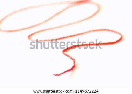 The German phrase "the thread of a story" abstractly depicted as a picture with a red thread in front of a white background - represents the inner consistency of a story