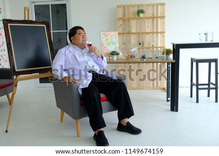 Doctor drinking wine, sitting on sofa in front of picture frame in the living room, rose wallpaper.