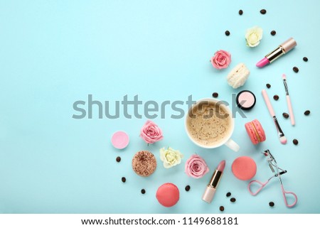 Rose flowers with cup of coffee and makeup cosmetics on blue background