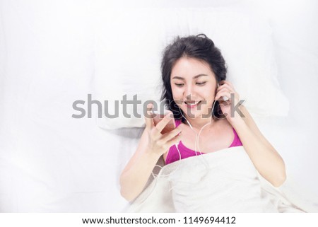 Asian young woman lie supine lying in bed with head on pillow comfortable and happy. Girl with relax in the music therapy for health concept.