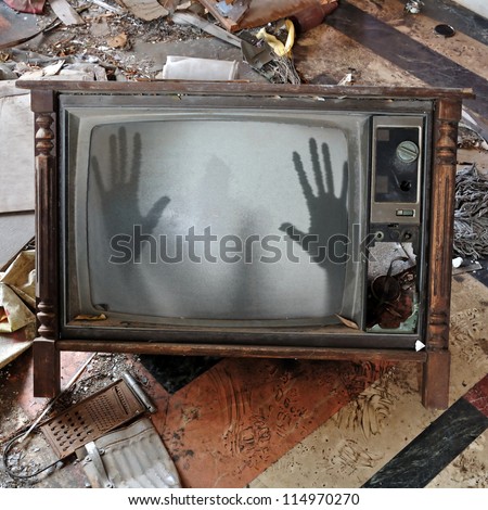 Ghost emerges through broken flickering television screen in haunted house. Royalty-Free Stock Photo #114970270