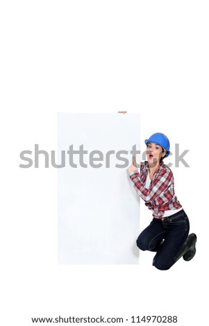 A female construction worker pointing at a poster.