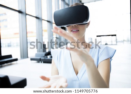 Young woman in vr goggles explaining something to her virtual audience while making presentation