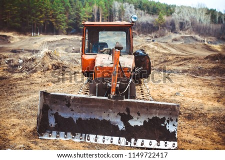Vintage bulldozer. An abandoned old tractor with a bucket on a stone quarry. Old tractor in the field