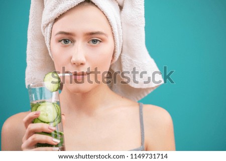 Attractive girl with towel on head, looking at camera with content, satisfied expression, drinking cold organic coctail through a straw. Cosmetics, cosmetology, dermatology. Royalty-Free Stock Photo #1149731714