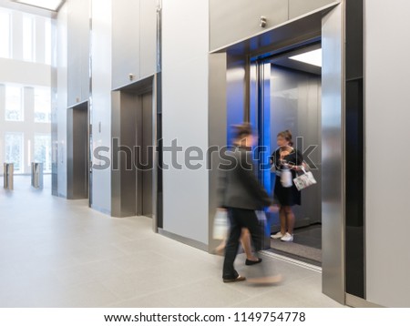 People are walking in office past elevators, Modern steel elevator cabins in aoffice lobby or Hotel.