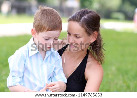 Young Mother and little son in autumn park. Concept of friendly family.