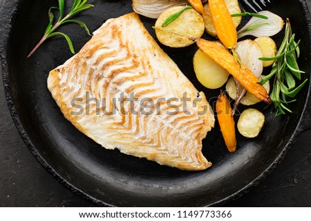 Cod fillet baked with fresh farmer's vegetables: potatoes, carrots, onions. Top View