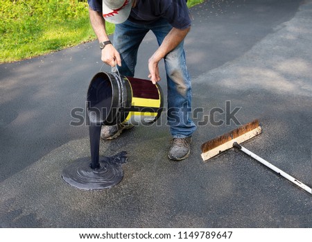 Do it yourself home maintenance. Driveway resealing repair. Homeowner pours blacktop sealant onto driveway Royalty-Free Stock Photo #1149789647