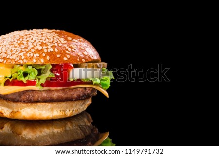 tasty burger on a black background. close-up hamburger. homemade burger with meat, cheese and fresh tomato, onions and lettuce      