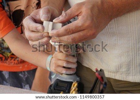 Father and son working on stone. Carving a stone seal. Metal drill bit make holes in stone figure. Plastic art workshop in the garden. Beautiful background art of making two- or three-dimensional form
