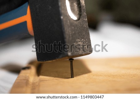 a hammer hits a nail on a wooden table