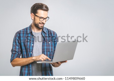 Confident business expert. Confident young handsome man in shirt holding laptop and smiling while standing against grey background 