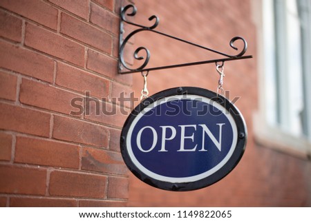 Blue colored open for business signage  hanging on a brick wall