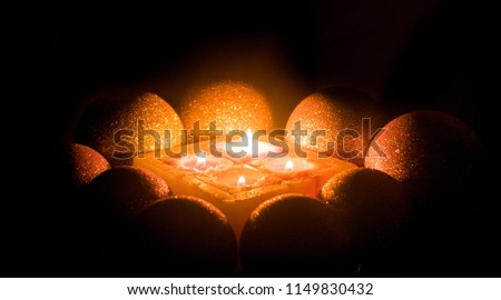 Burning candles surrounded by shiny balls on a dark background.