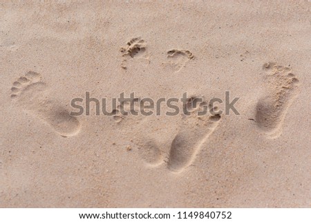 footprints of people on the sand during the day, adults and child