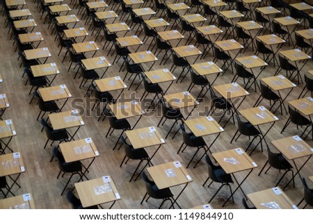 Hall with empty wooden desks and plastic chairs, ready to be used for examination purposes. Royalty-Free Stock Photo #1149844910