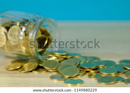 Coins stacks and gold coin money in the glass jar on table with green background, for saving for the future banking finance concept idea.