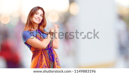 young beautiful girl smiling and pointing upwards with both hands, towards the place where the publicist may show a concept.
