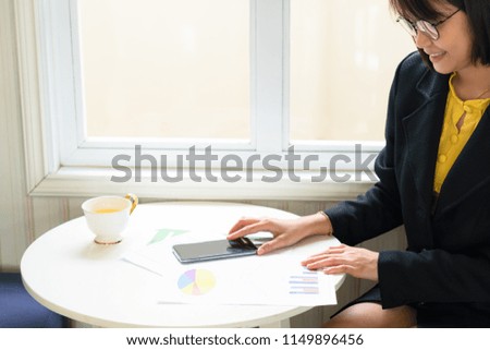 Business woman analyzing income charts and graphs  and using smart phone