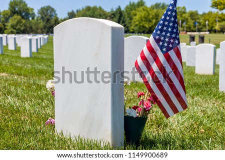 The United States National flag with white headstones in the background in Camp Butler National cemetery