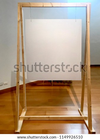 Wooden Easel Mockup standing with blank canvas or craft paper on wooden flooring for billboard or information maker