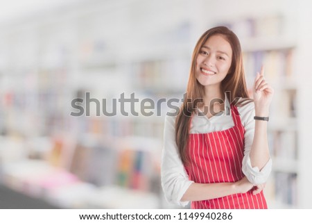 Portrait of Smiling beautiful young Asian woman wear red apron and hand pointing with copy space for your text or advertising isolated on white.