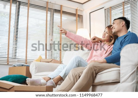 Asian couple planning to decorate house after moving to new home,sitting on sofa with relax emotion.