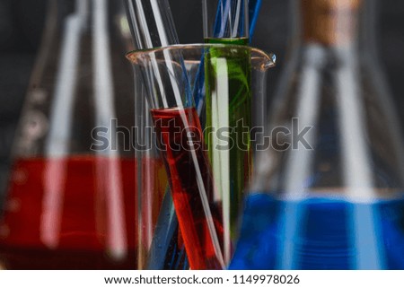 School supplies. Tubes with chemical liquids stand on a wooden table on a chalkboard background with digital formulas