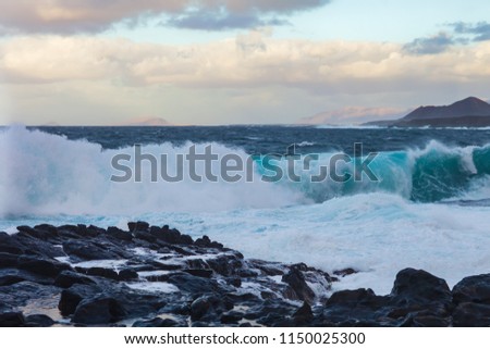 Breaking ocean wave on rock coast with spray and foam in Canary islands. Nature background