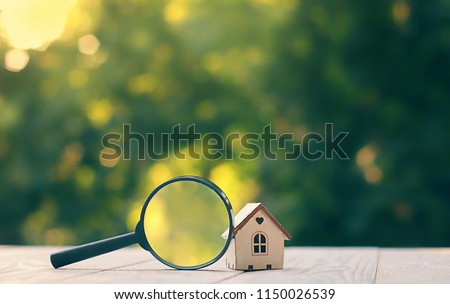 mini house and magnifying glass, natural green background. House searching, choice of location for construction, of mortgage, rental housing. construction, sales, lease, home realtor business concept
