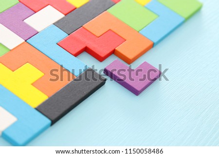 A colorful square tangram puzzle, over wooden table