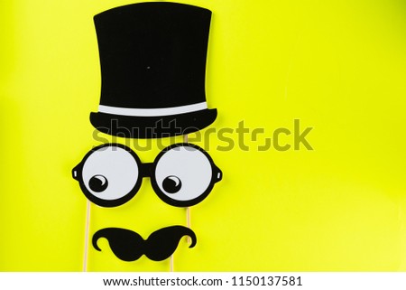 Top view image of  funny masks glasses, hat and mustache on yellow background.Birthday Halloween Father day, Purim, Fool day concept.