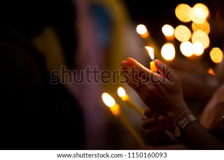 Hand protects the flame from being blown away. Orange light in the dark to worship good. And to express love.