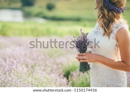 Bride is holding the bouquet with lavender flowers staying on the lavender field. Lavender field.