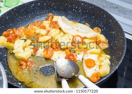 cod cooked in a pan, with tomato, potatoes and capers