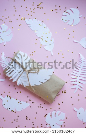 present on craft paper and  paper tropical leaves and glitter. gift box wrapping. decorating idea.